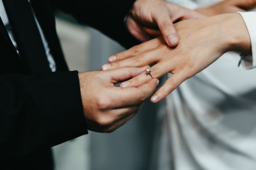 Free A groom places a wedding ring on the bride's finger during a close-up ceremony shot. Stock Photo