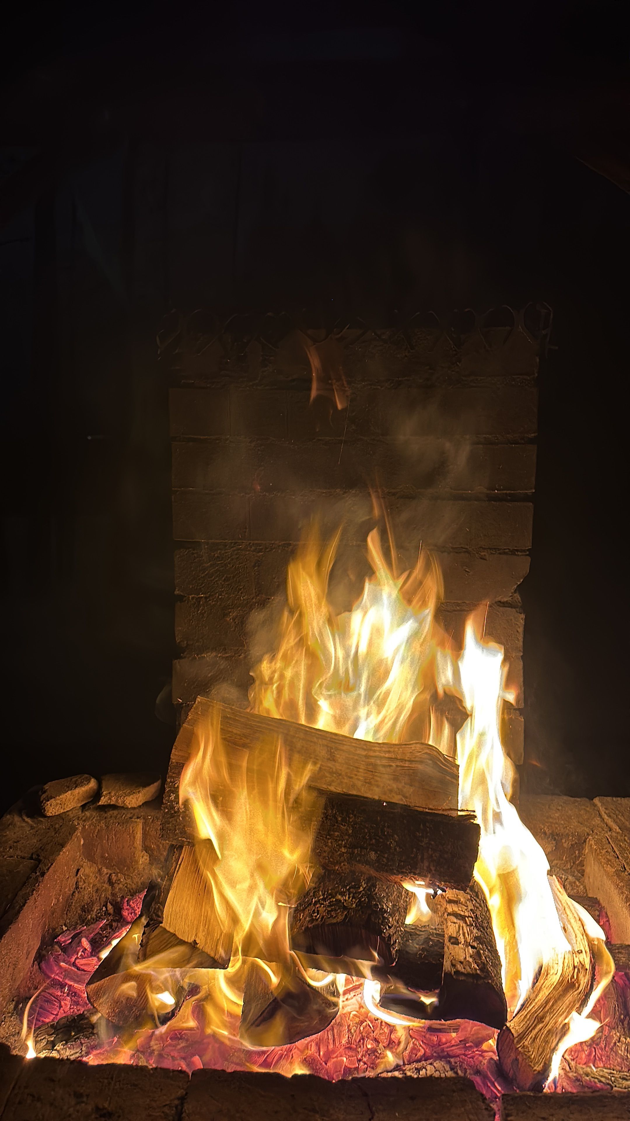 Warm glowing fireplace with logs and bright flames, ideal for cozy winter settings.