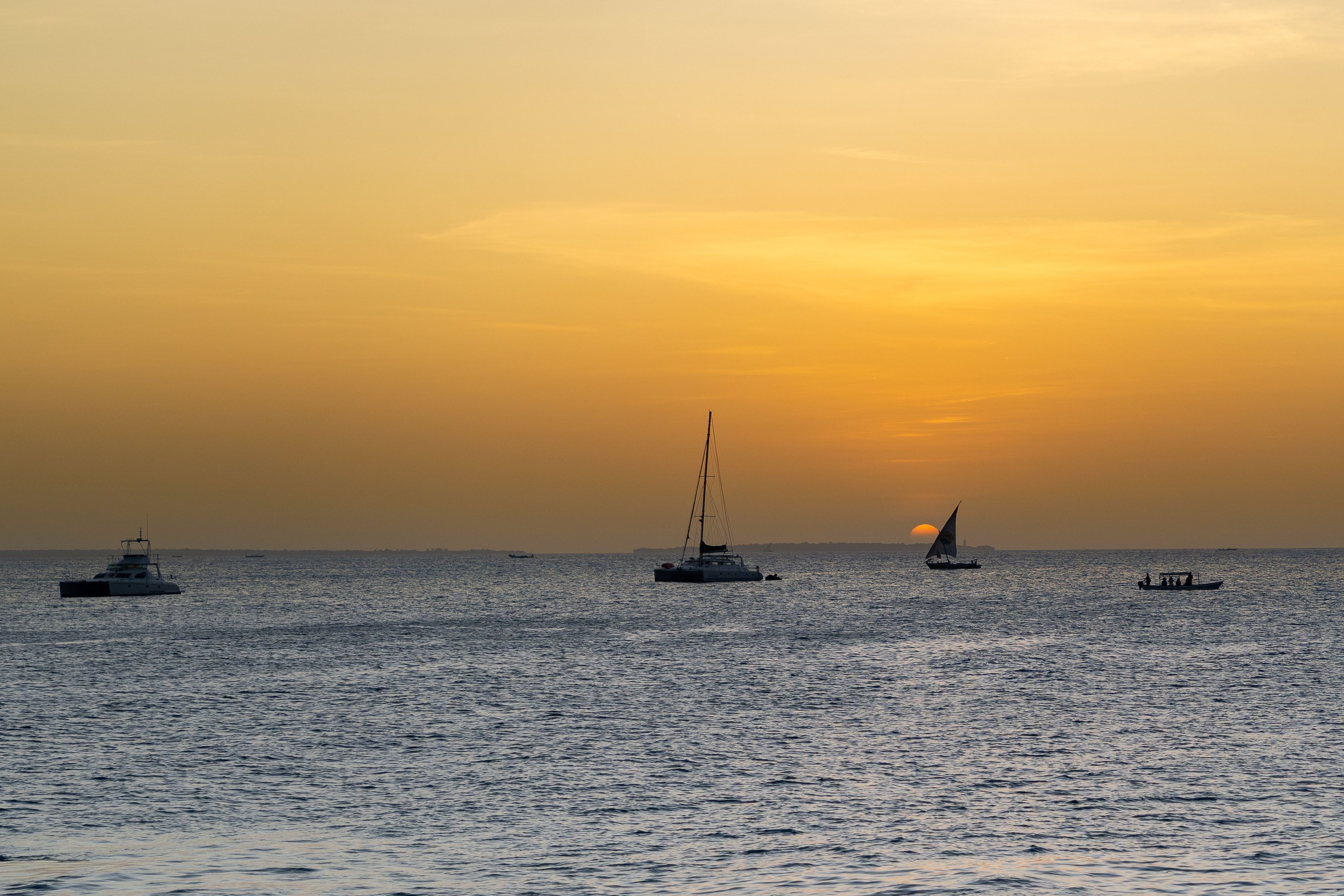 Serene evening view with boats during a beautiful Zanzibar sunset over the ocean horizon.
