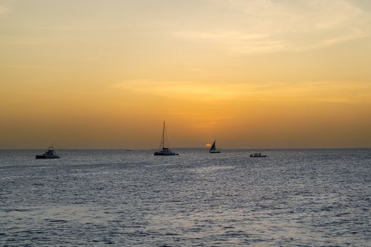 Boats sailing during a tranquil Zanzibar sunset, offering a serene tropical view.