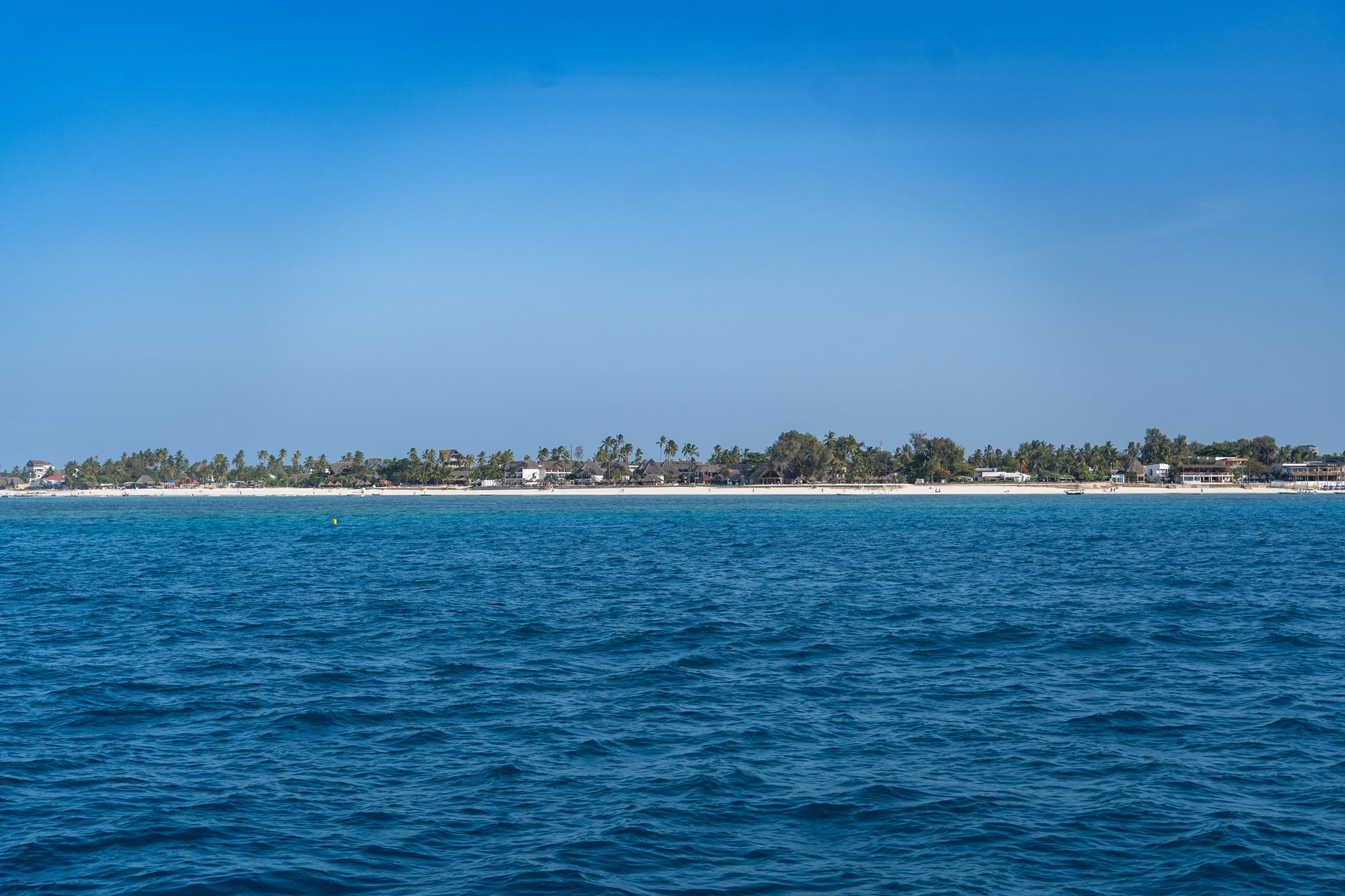 Discover the serene beauty of Zanzibar's coastline with pristine turquoise waters and lush palm trees.