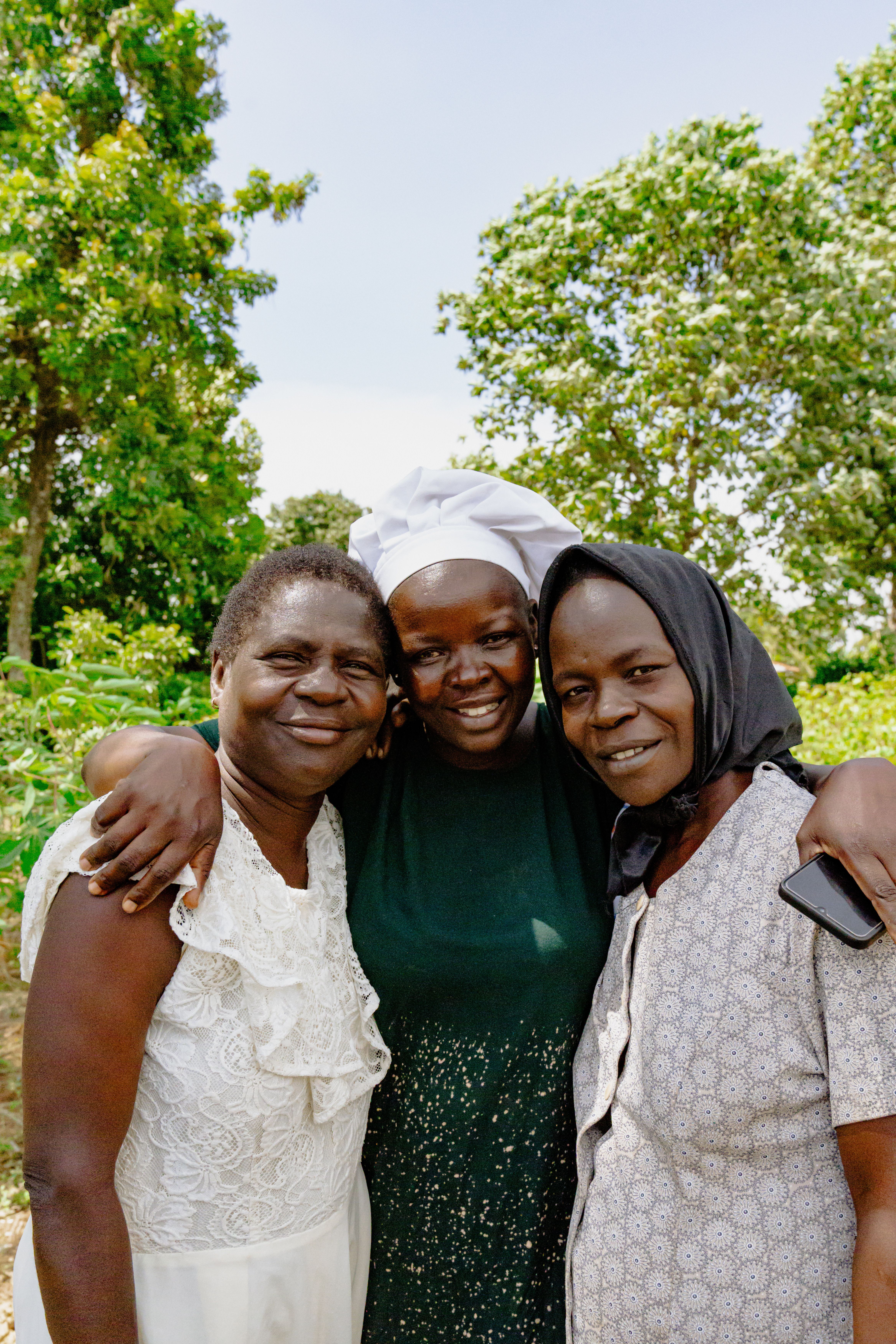 Community members gathered under a tree in Mukono District, talking with Acred Hill of Hope staff