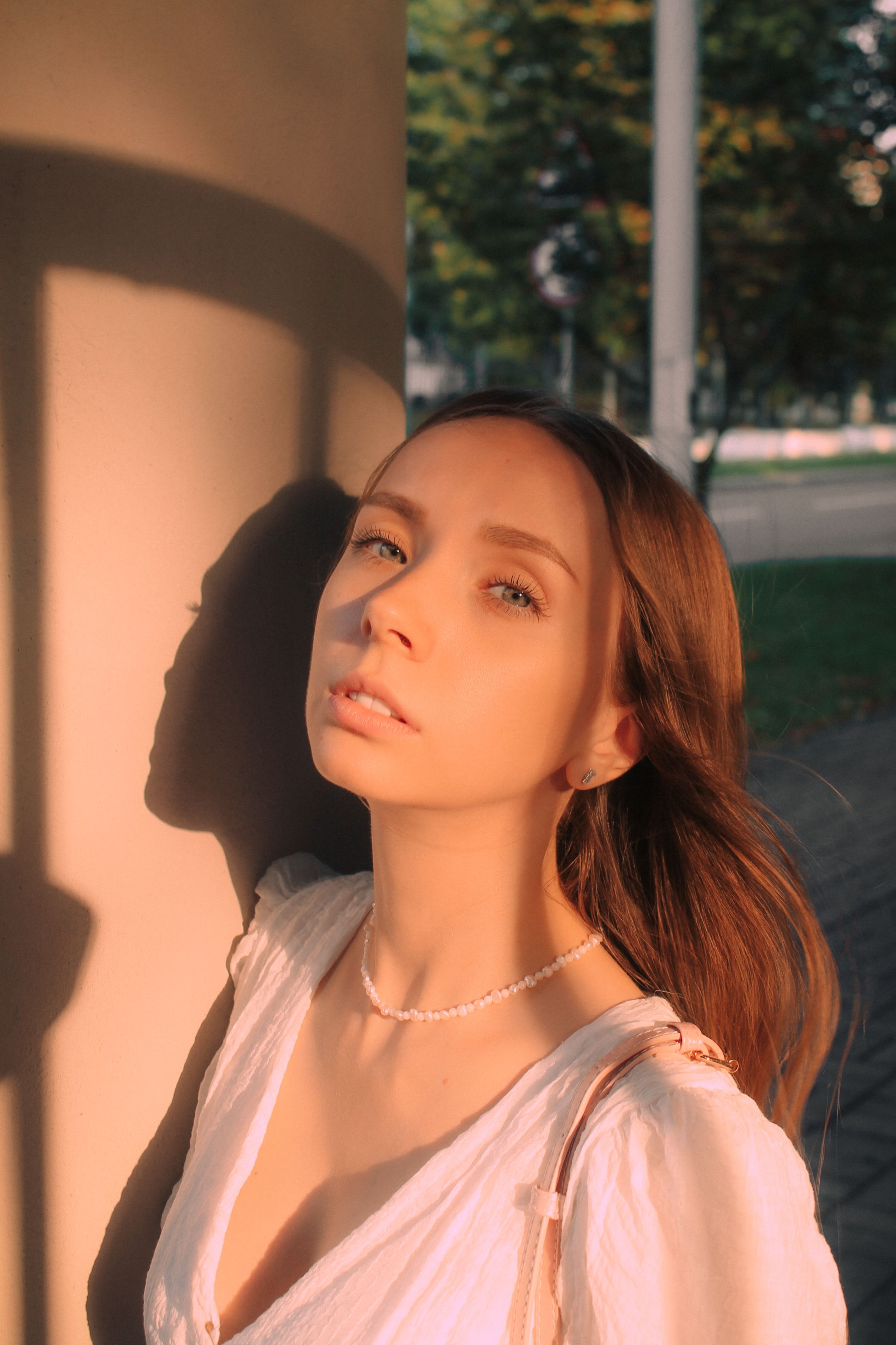 Elegant portrait of a woman bathed in warm, golden hour sunlight, outdoors.