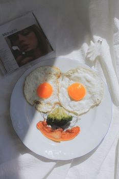 Artistic breakfast plate with eggs and vegetables creating a smiley face design.