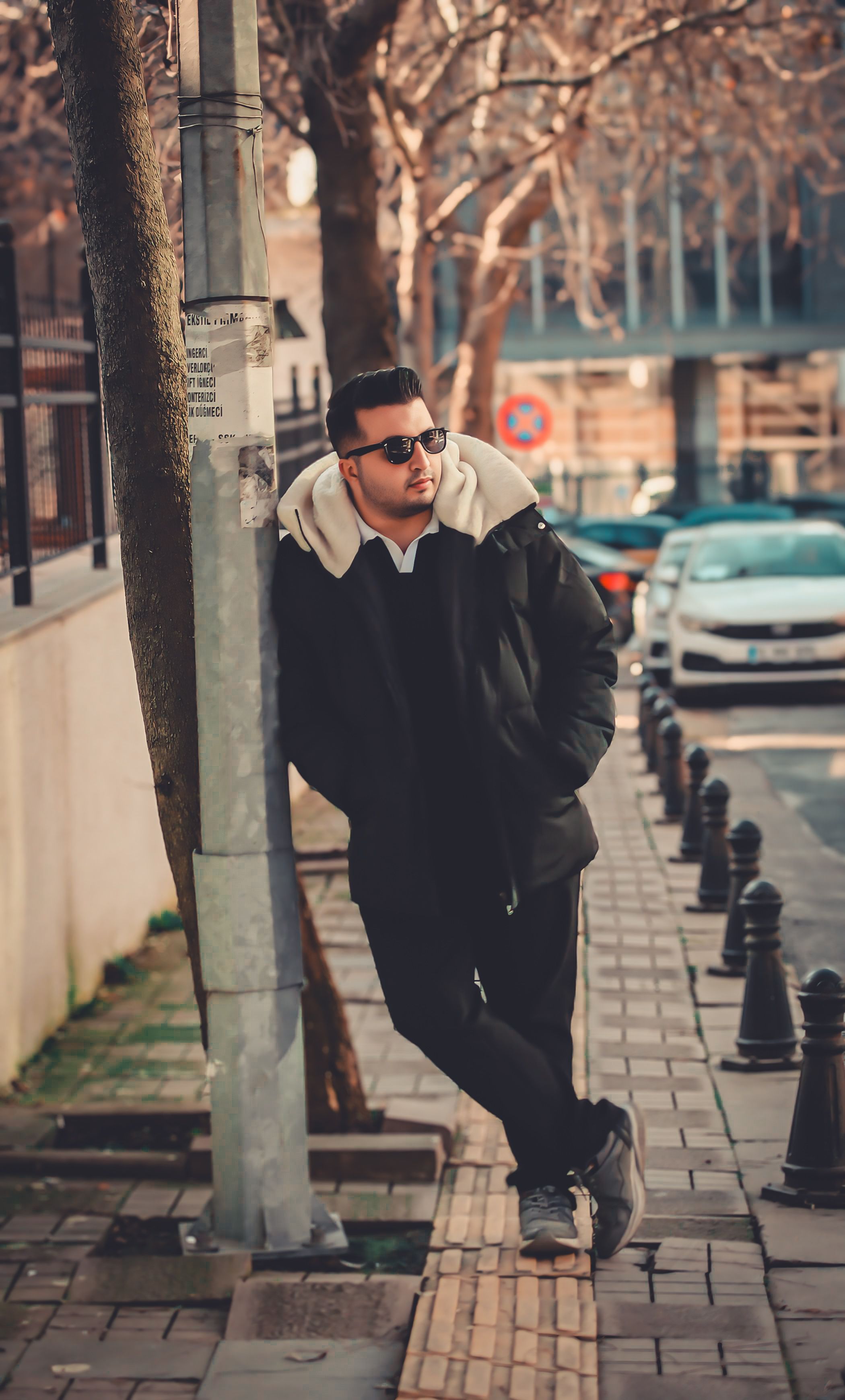Casually dressed man in urban setting leaning against a streetlight