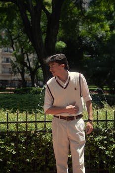 Portrait of a stylish young man standing confidently in a sunny Buenos Aires park.