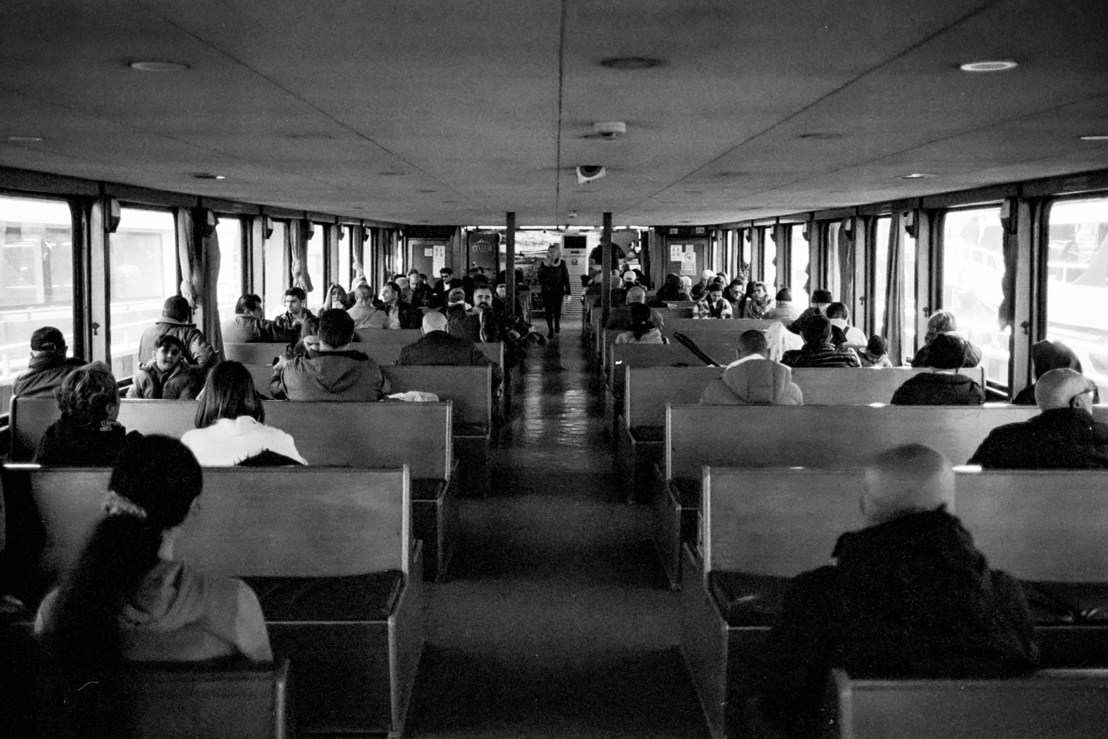 Passengers seated inside a ferry in Istanbul. Black and white photography.