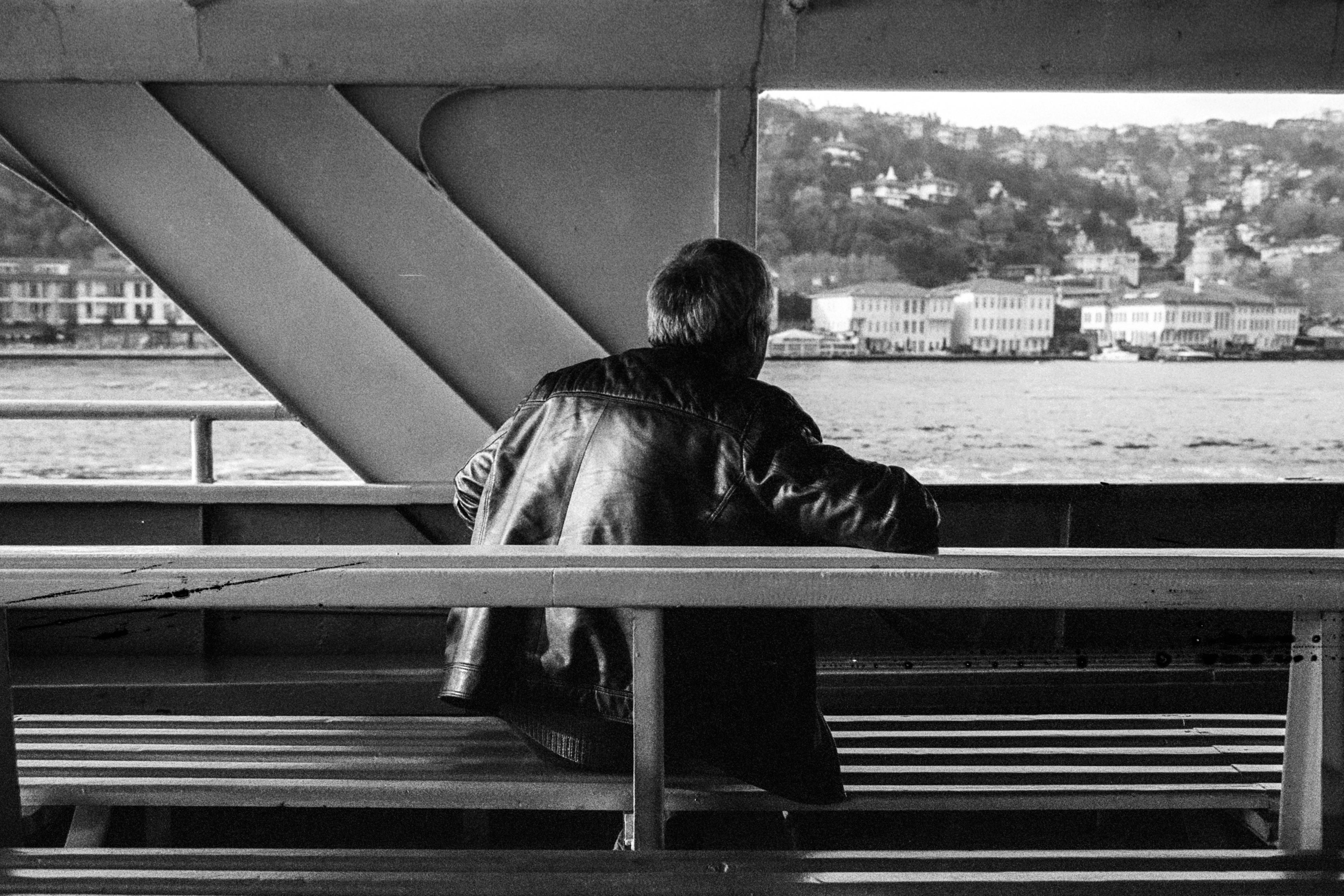 A black and white photo of a person sitting alone on a ferry in İstanbul, Türkiye.
