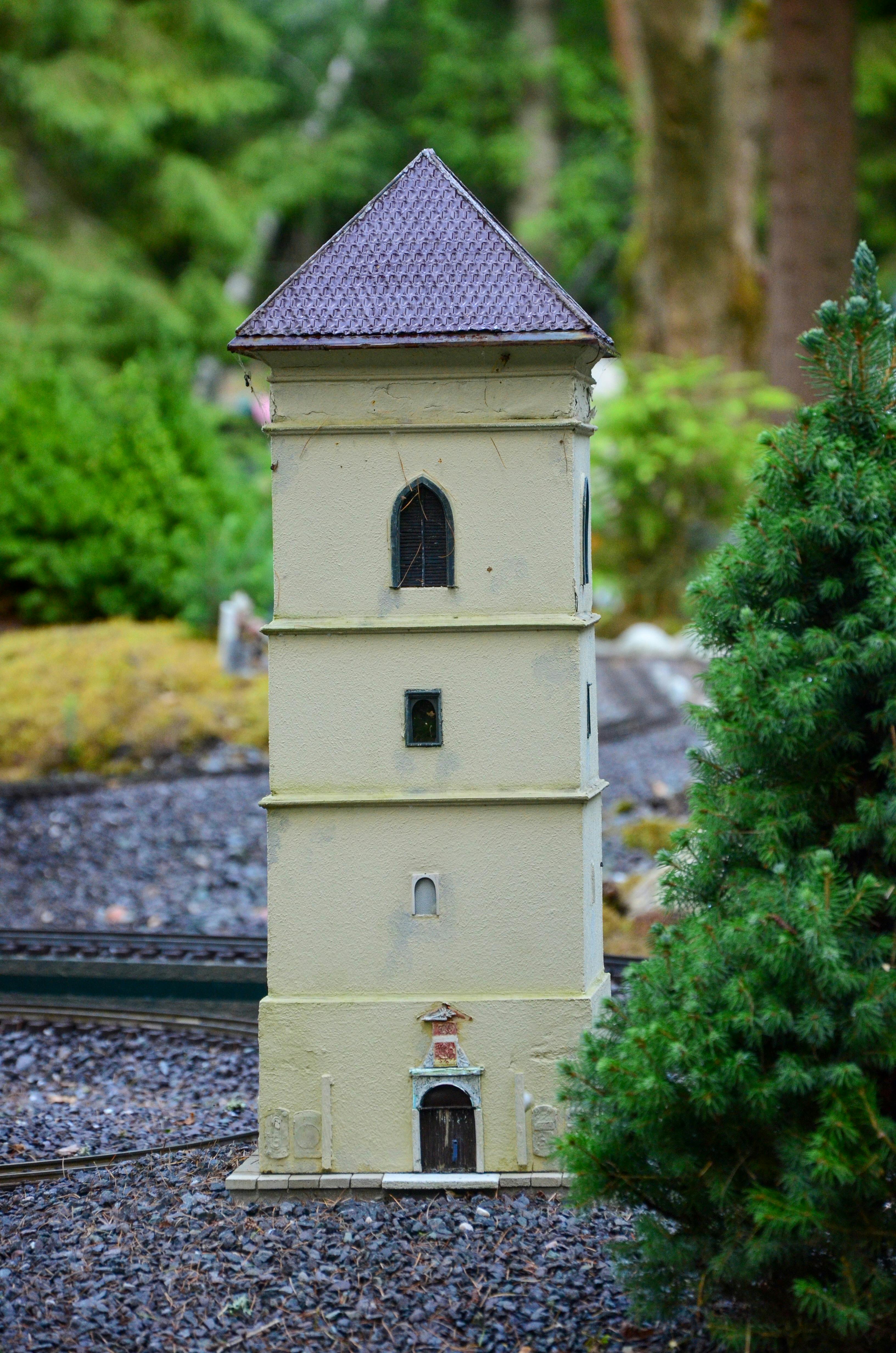 Gratis Model menara miniatur terperinci yang dipajang di luar ruangan dan dikelilingi tanaman hijau. Foto Stok