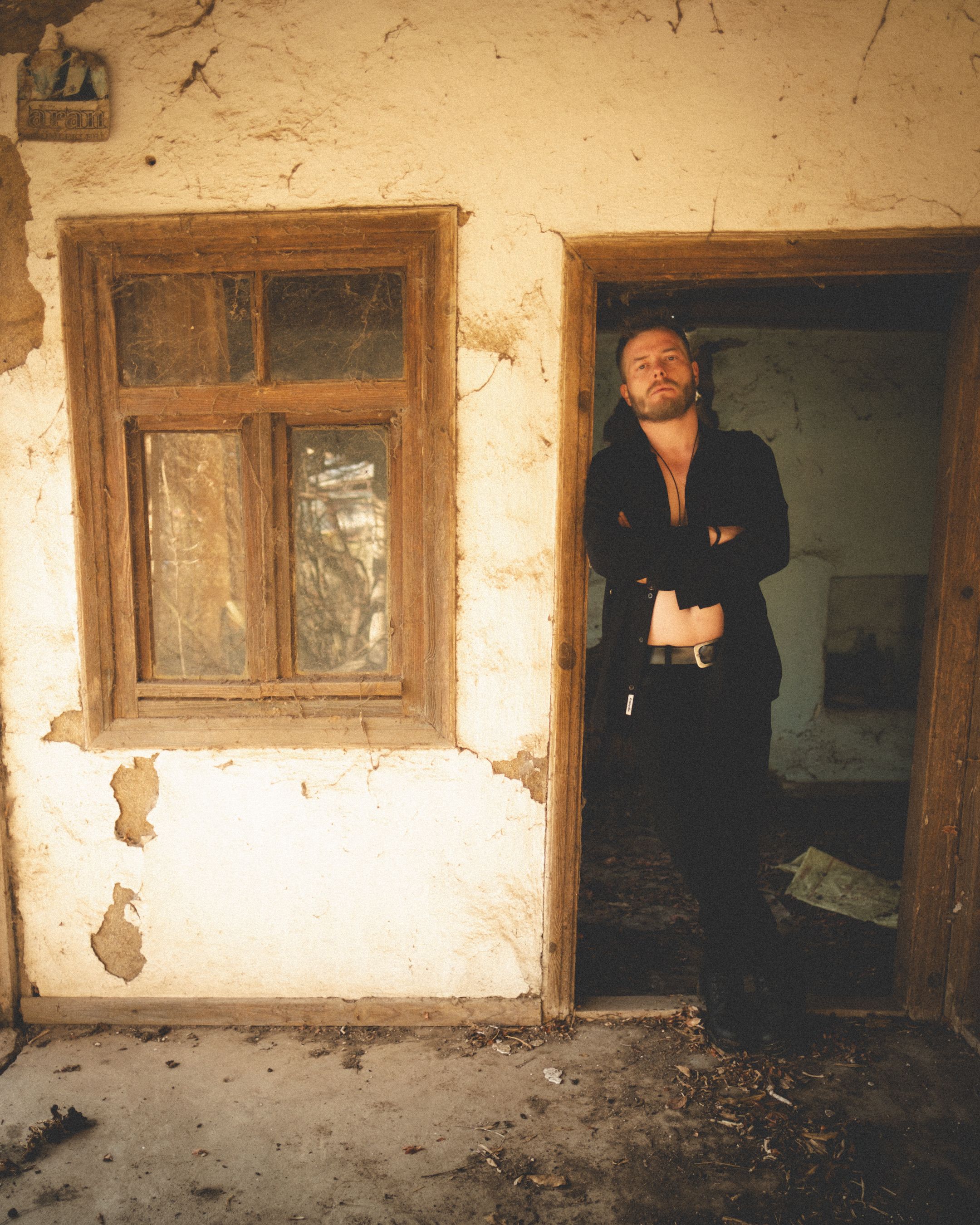 A man stands in the doorway of a rustic, abandoned house in Türkiye.