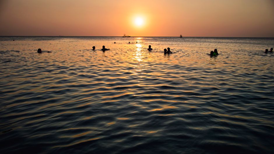 People swimming during a beautiful sunset in Santa Marta, Colombia.