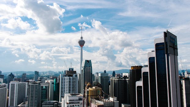 Aerial view of Kuala Lumpur's skyline with iconic KL Tower on a clear day.