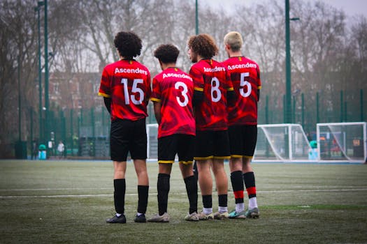 Four soccer players in red jerseys stand on the field, preparing for the game.