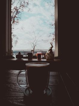 A warm coffee cup by a window with a scenic winter view, creating a cozy atmosphere.