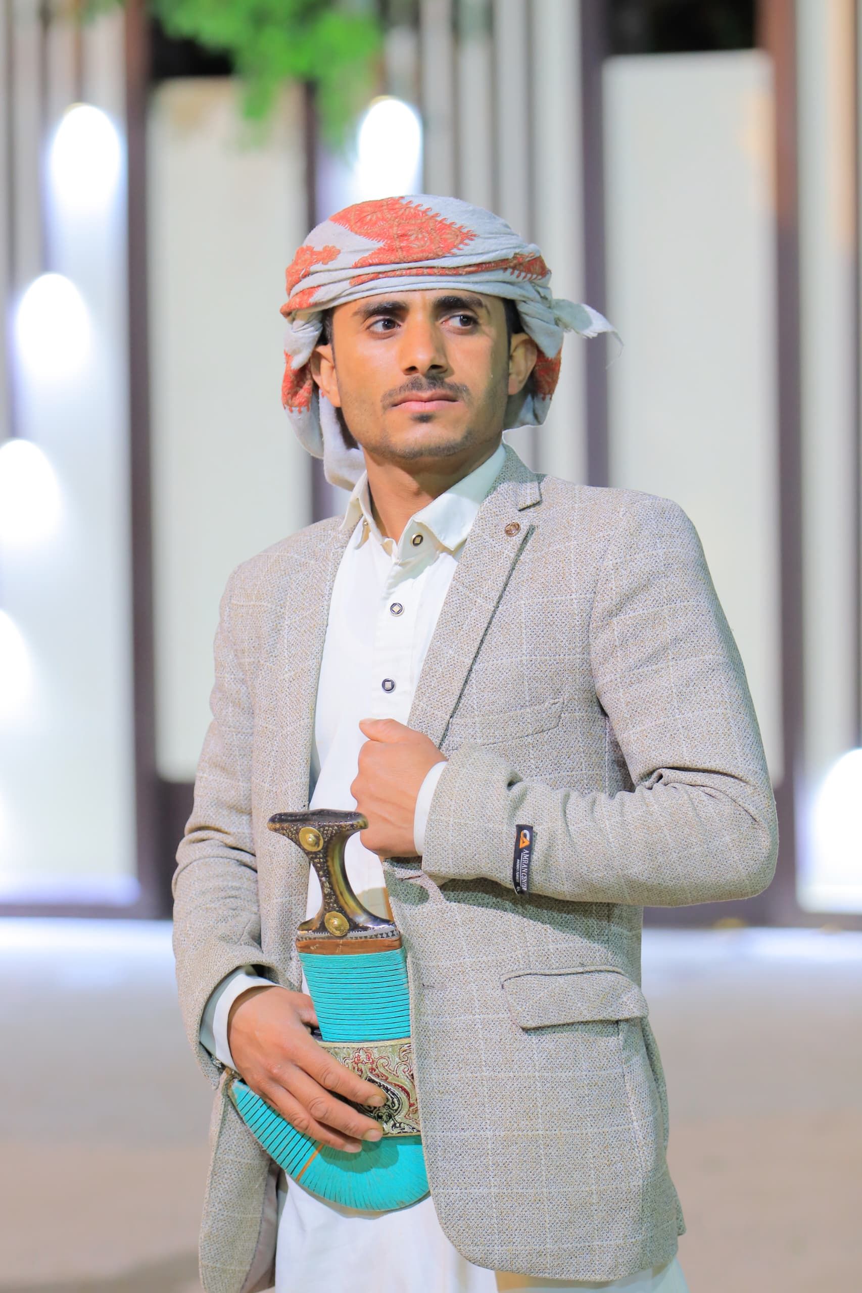 Man in traditional attire holding a jambiya in a modern setting.