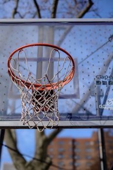 Close-up of outdoor basketball hoop with net and clear sky background.