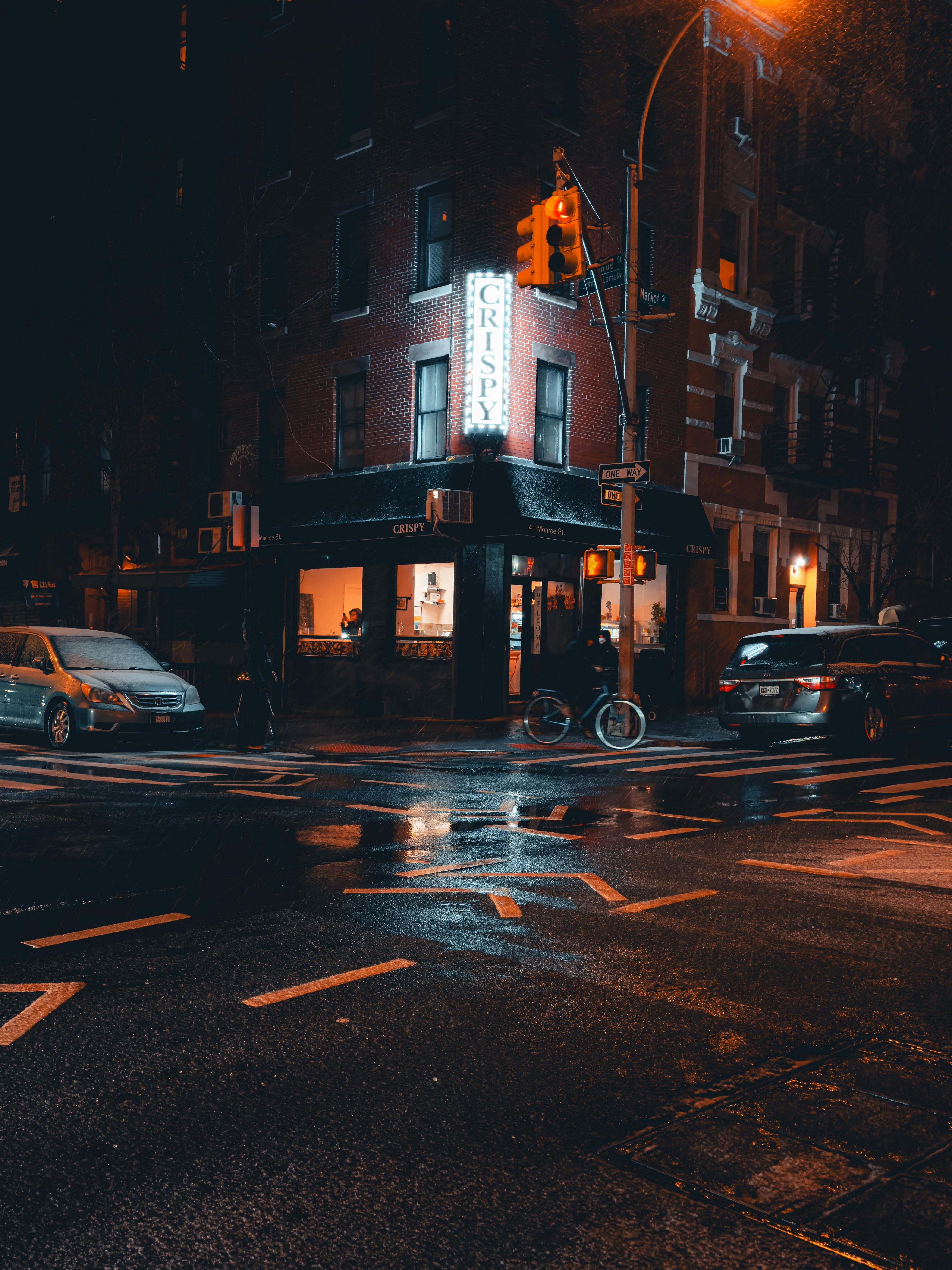 Rain-soaked street at night with glowing neon sign and reflections.