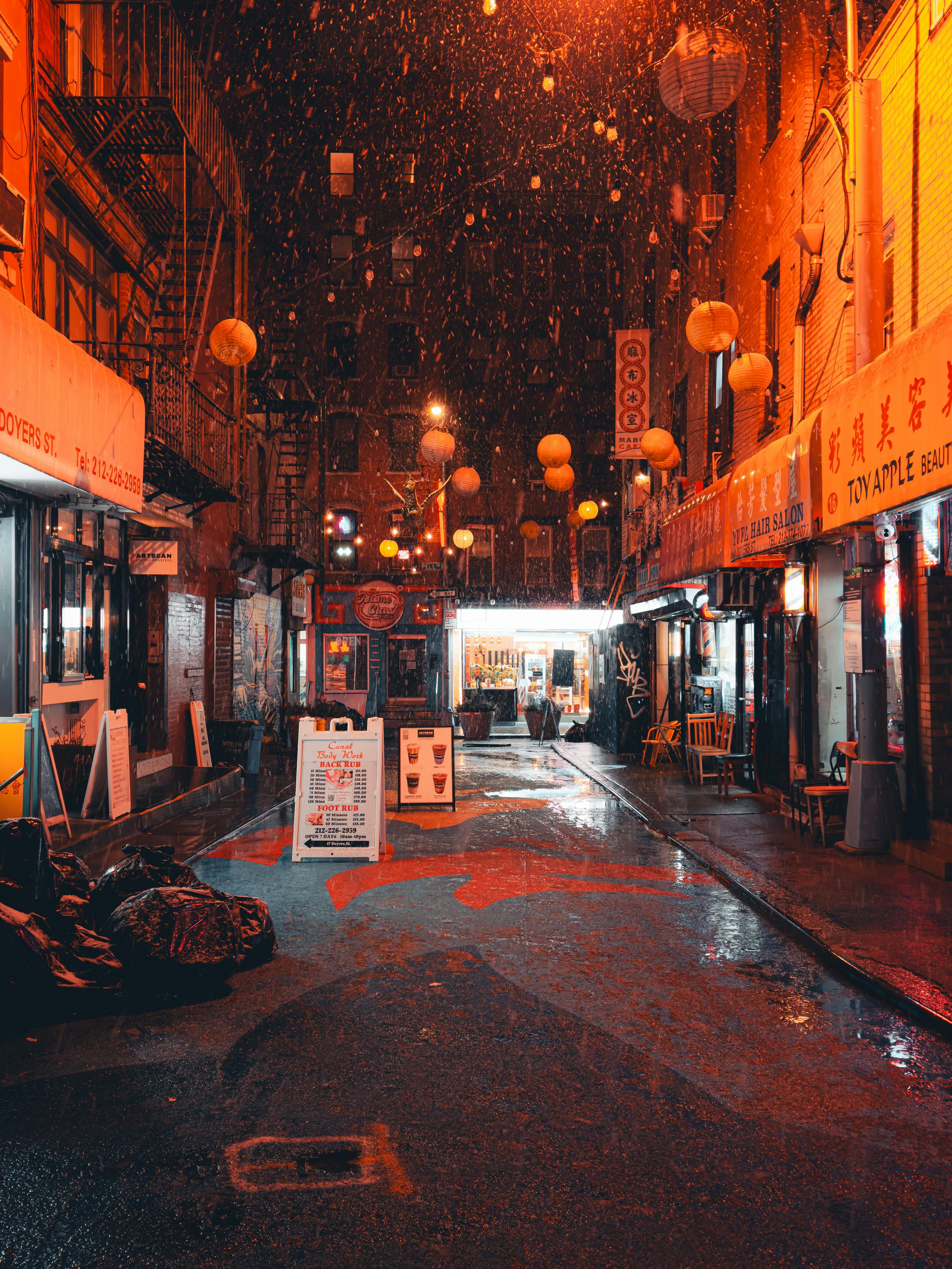 Atmospheric photo of a Chinatown street at night, illuminated by lanterns and glowing signs.