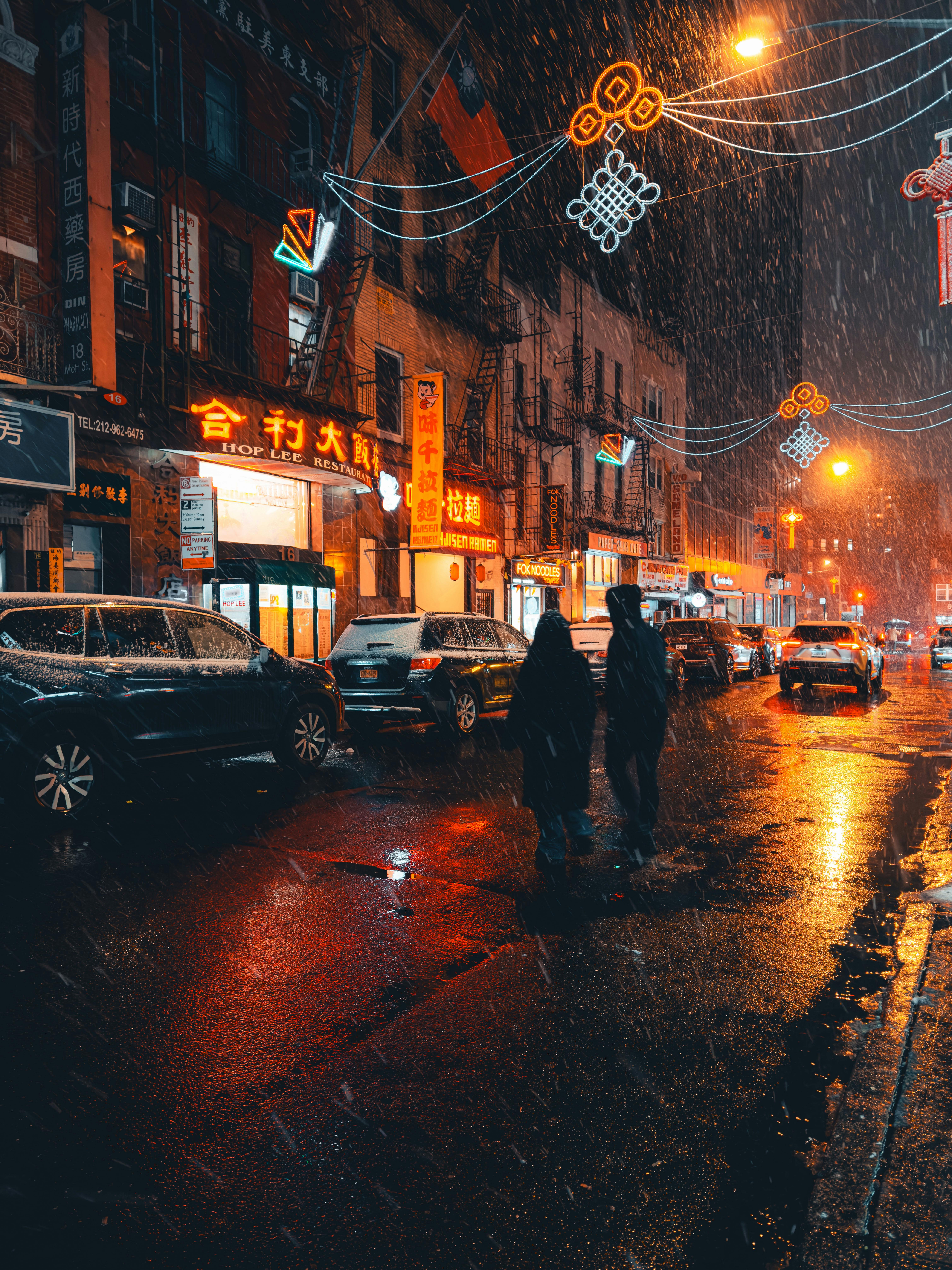 Vibrant city street with neon signs and people walking on a rainy night.