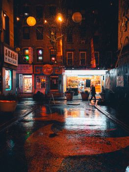 A captivating night scene capturing a rainy city alleyway illuminated by colorful lights, creating a vibrant urban atmosphere.