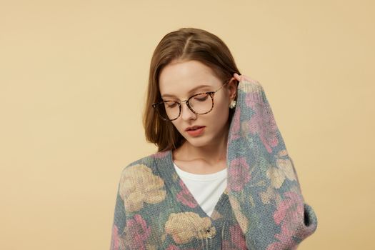 Portrait of a woman wearing stylish eyeglasses and a floral sweater in a photo studio.