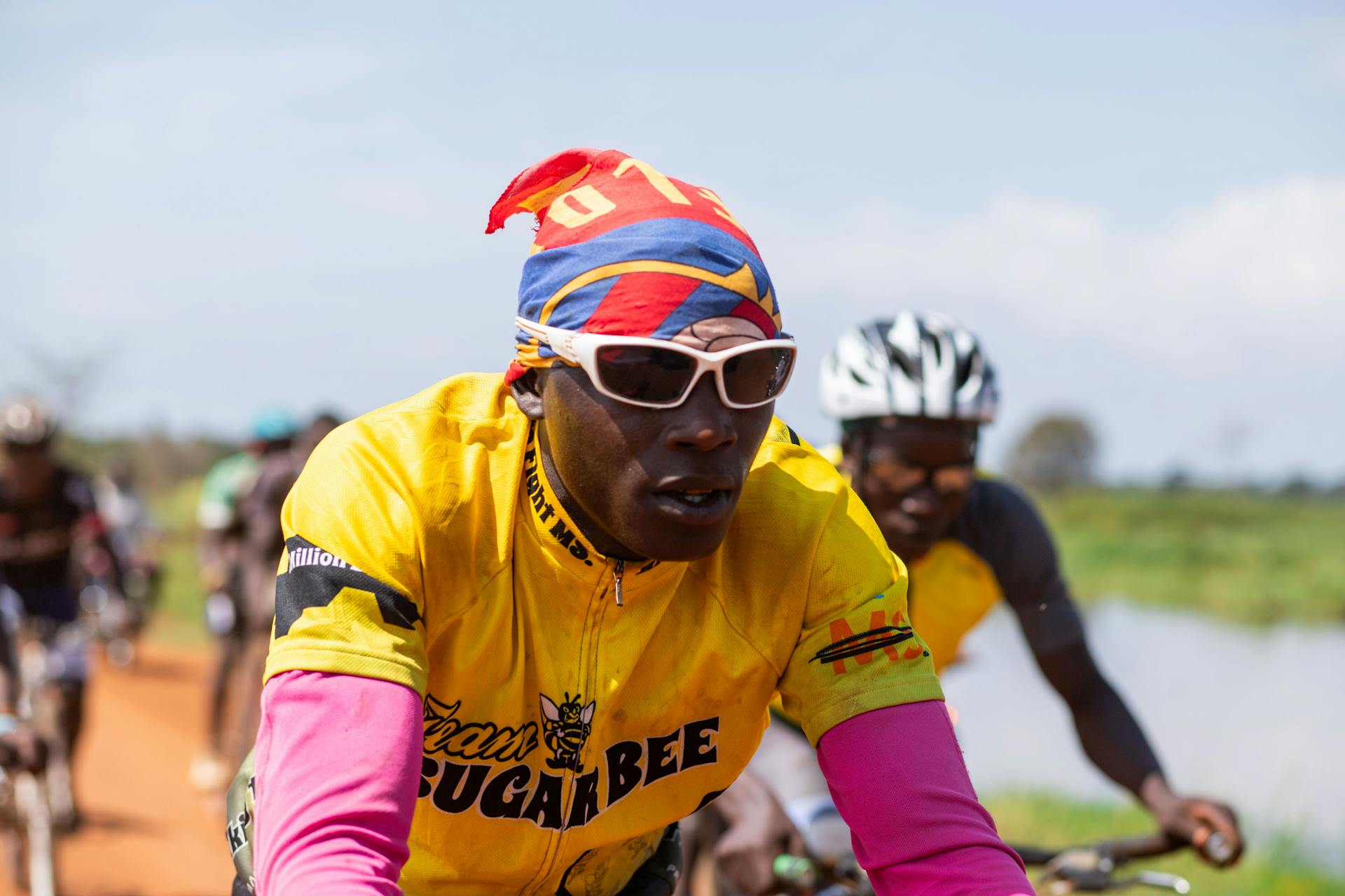 Cyclists competing in a vibrant outdoor race, wearing colorful attire on a sunny day.