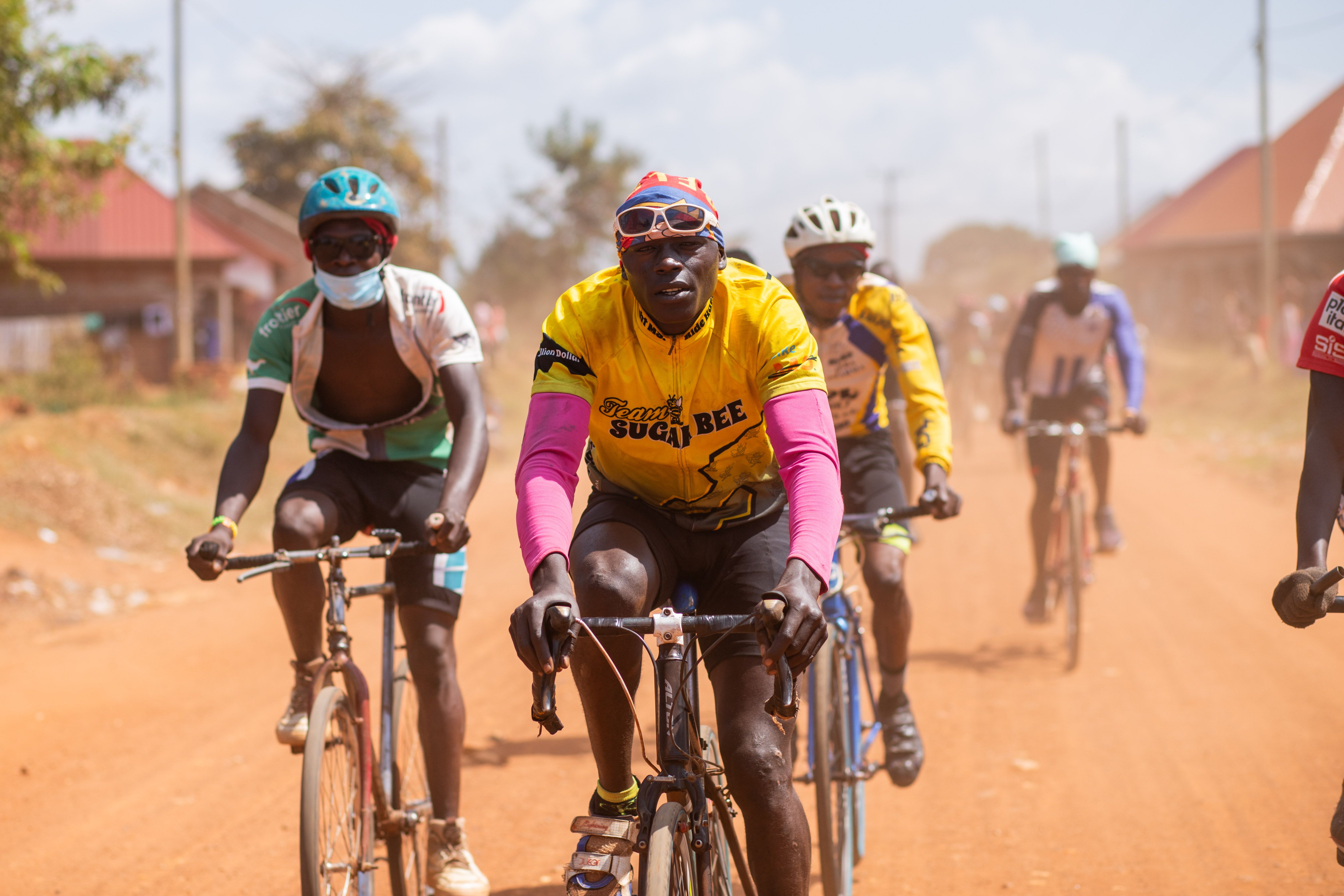Group of cyclists participating in a race on a dusty rural pathway under a bright sky.