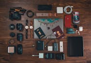 将旅行必需品，如小工具、护照和相机，放在木制表面上