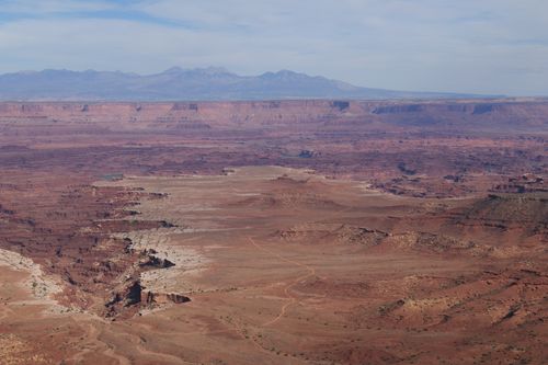 Free A breathtaking aerial view of a vast red desert landscape with distant mountains under a clear sky. Stock Photo