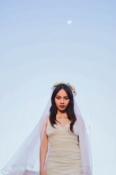 一位新娘穿着白色连衣裙、头戴花冠，在晴朗的天空下于户外摆姿势