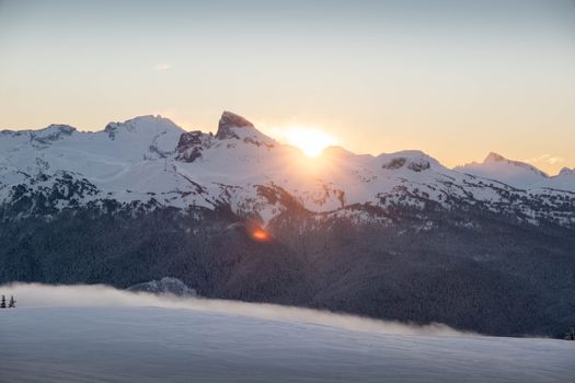 Stunning sunrise over snowy mountain peaks in British Columbia, capturing the beauty of winter nature.