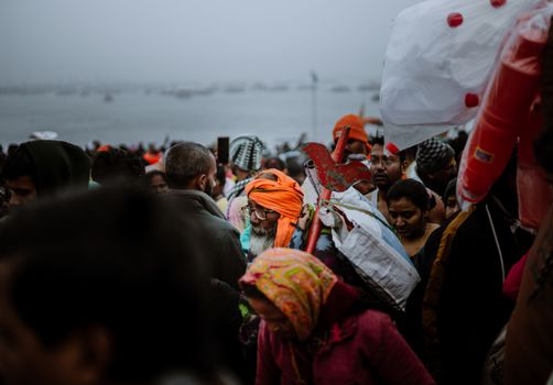 Vibrant crowd of diverse individuals gathering near a river during a cultural festival.