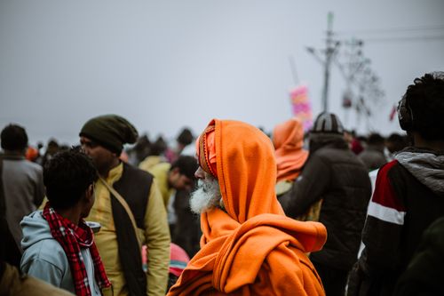 Free A crowd of diverse people gathered during a foggy day, with focus on a man in orange robes. Stock Photo
