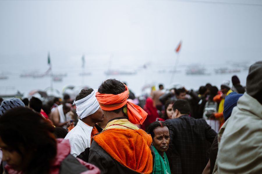 A vibrant riverside gathering with a diverse crowd, showcasing cultural attire and community spirit.