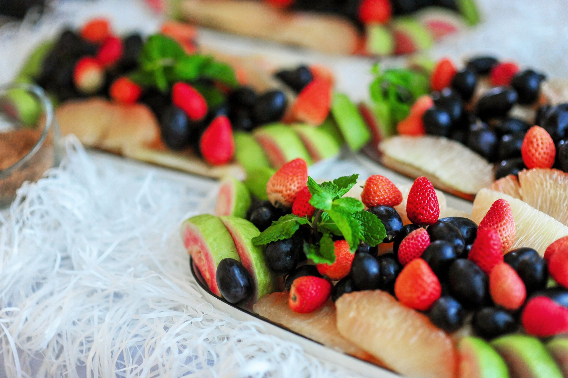 Colorful platter featuring fresh strawberries, grapes, and guava with a touch of mint garnish.
