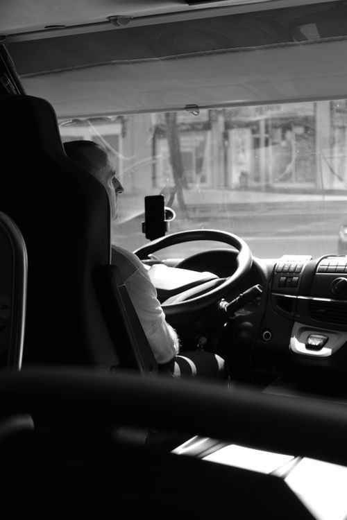 Free Black and white photo of a bus driver in Barcelona, Spain, providing a candid street view. Stock Photo