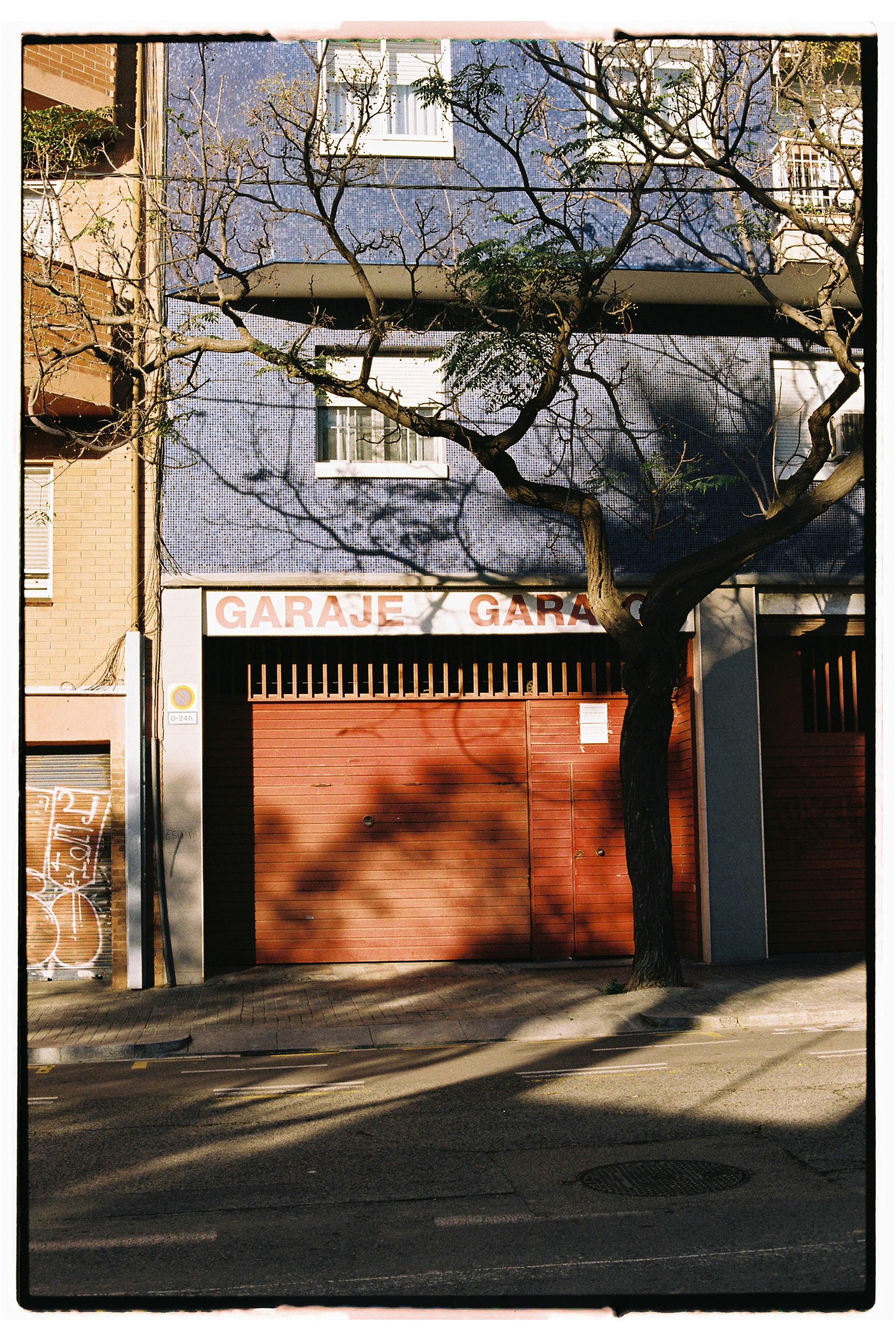 A city garage entrance with shadow patterns from a tree in sunlight.