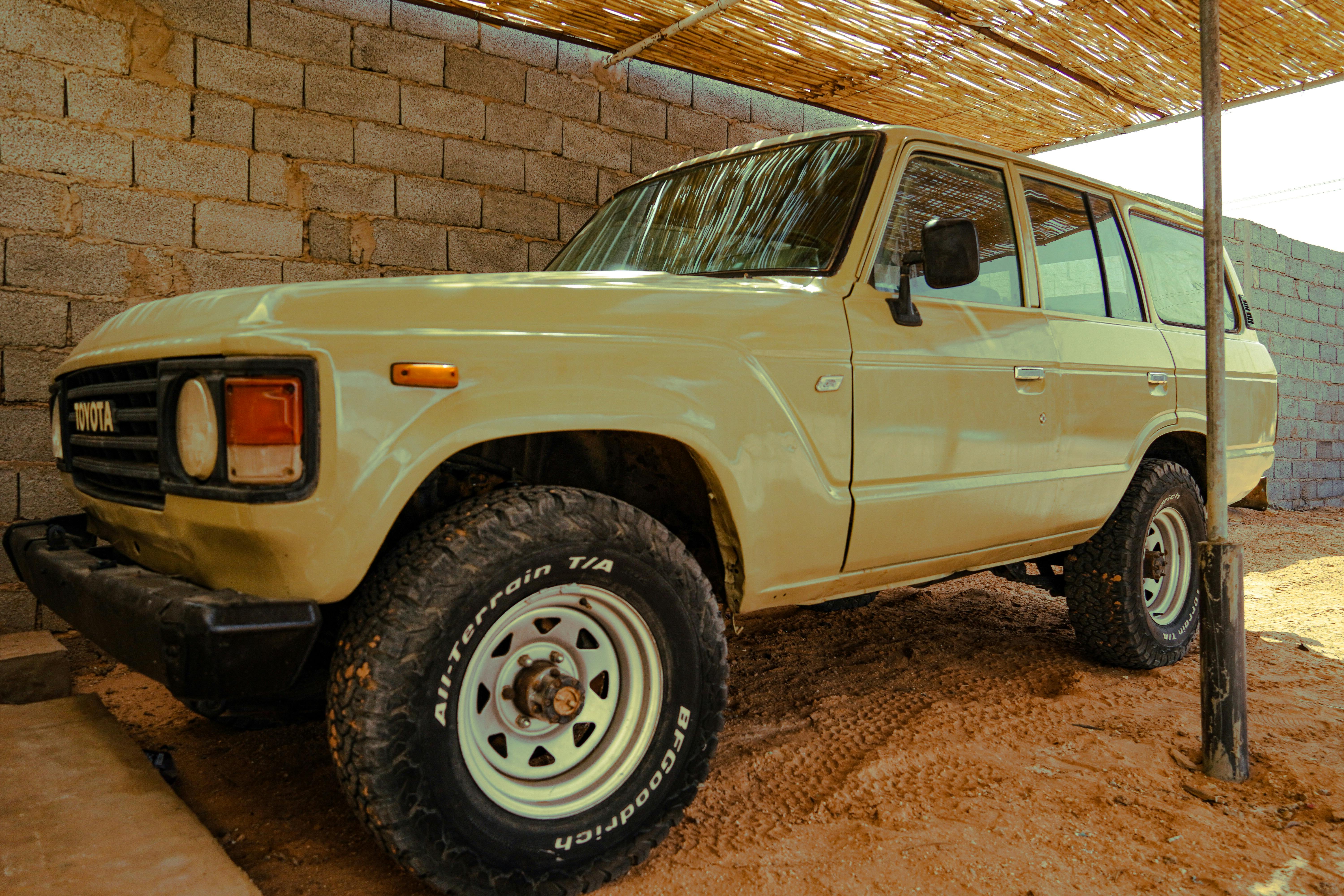 Classic beige SUV parked in a rustic, sunlit environment, showcasing its rugged design.