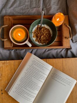 A serene morning scene with a breakfast tray, candlelight, and an open book.