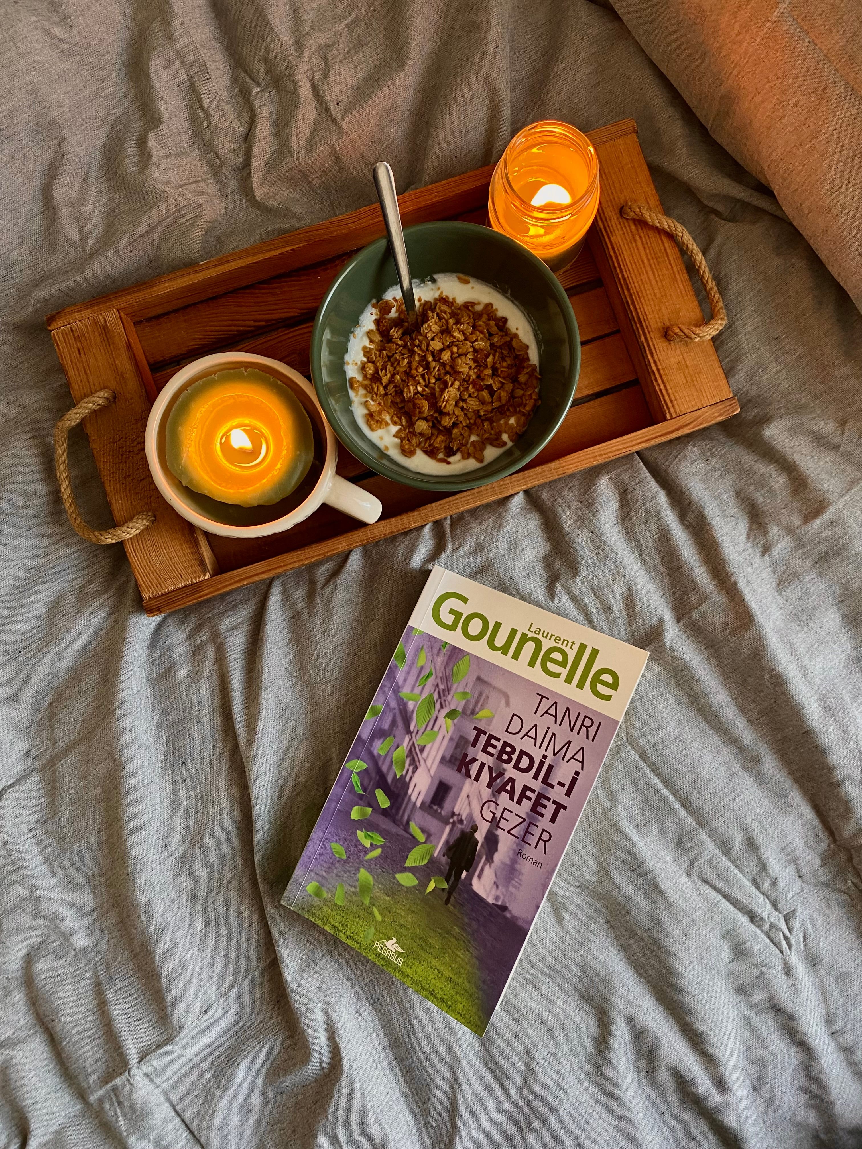 Warm morning scene with breakfast, candles, and a book on a wooden tray.