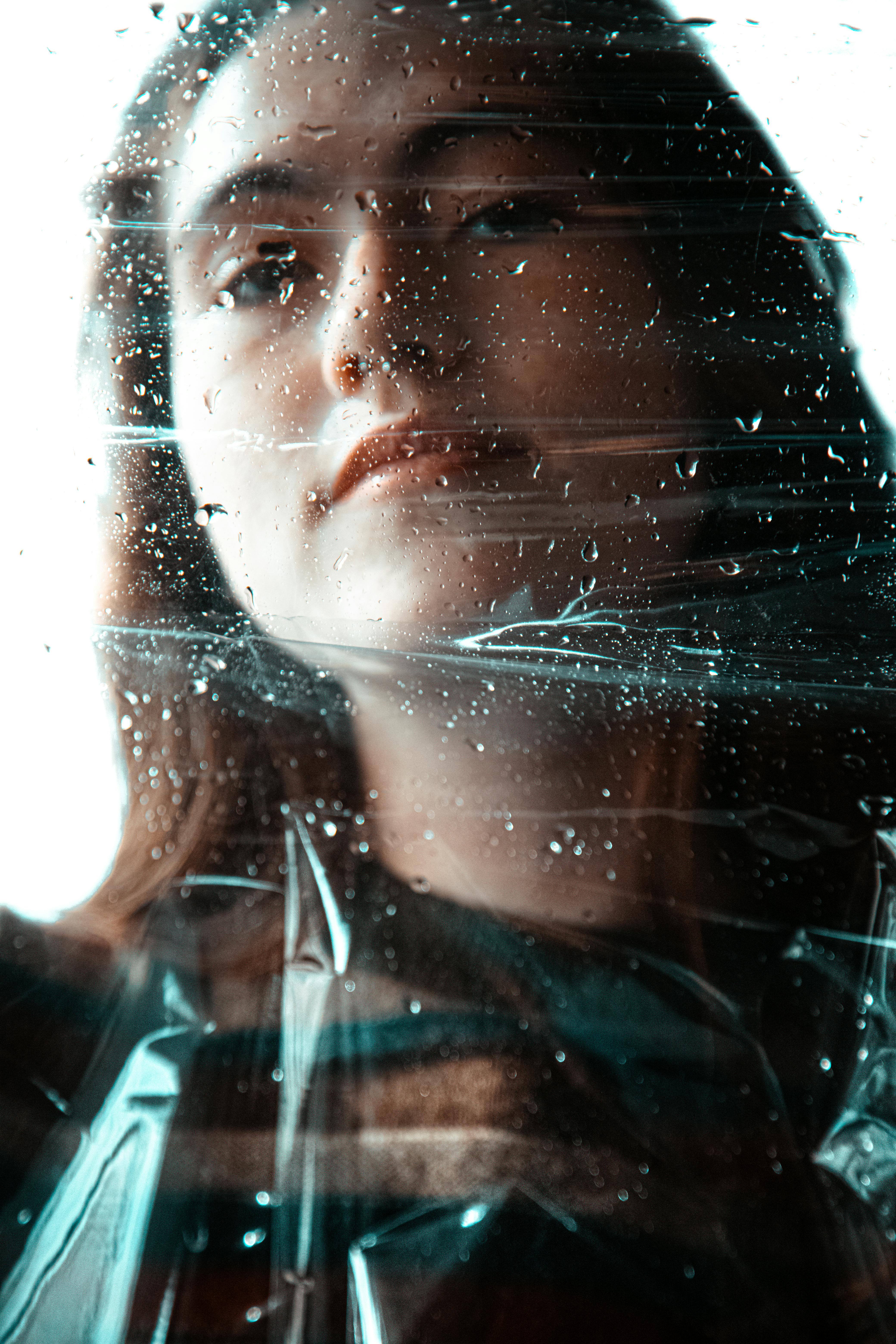 artistic portrait of woman behind rainy window