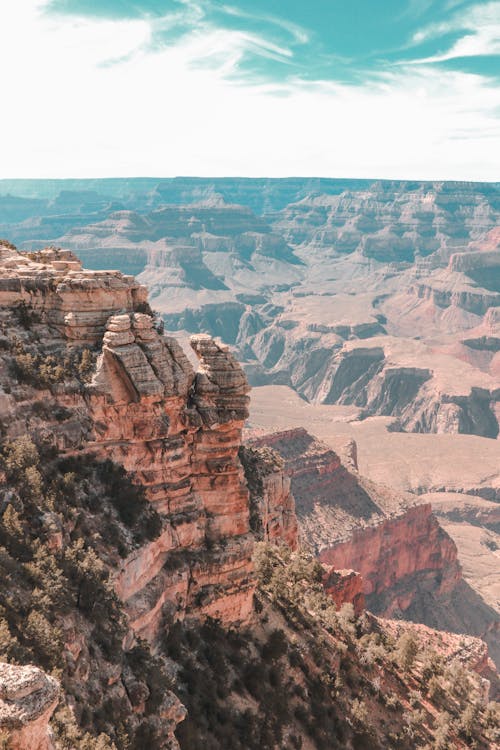 From above of huge rocky cliff located above canyon with stony formations against cloudy sky in daylight in nature outside