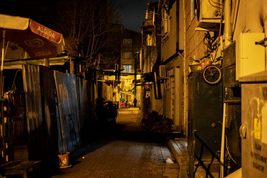 Street view of a narrow urban alley at night, creating a moody atmosphere with warm lighting.