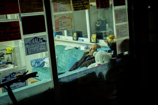 A man resting on a couch in an office with rental signs on the window at night.