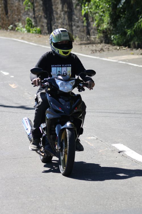 Free A motorcyclist in protective gear rides on a sunny urban road, showcasing safe travel. Stock Photo