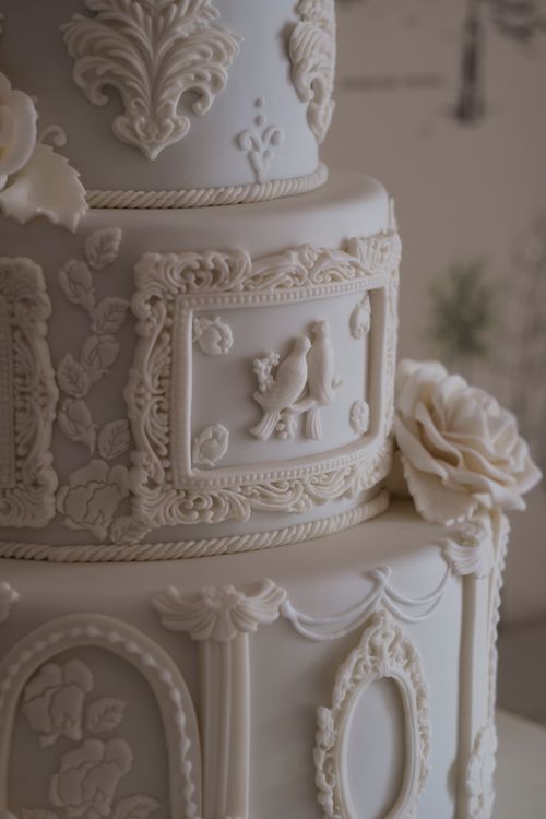 Free Close-up of a beautifully ornate white wedding cake with intricate floral and bird details. Stock Photo