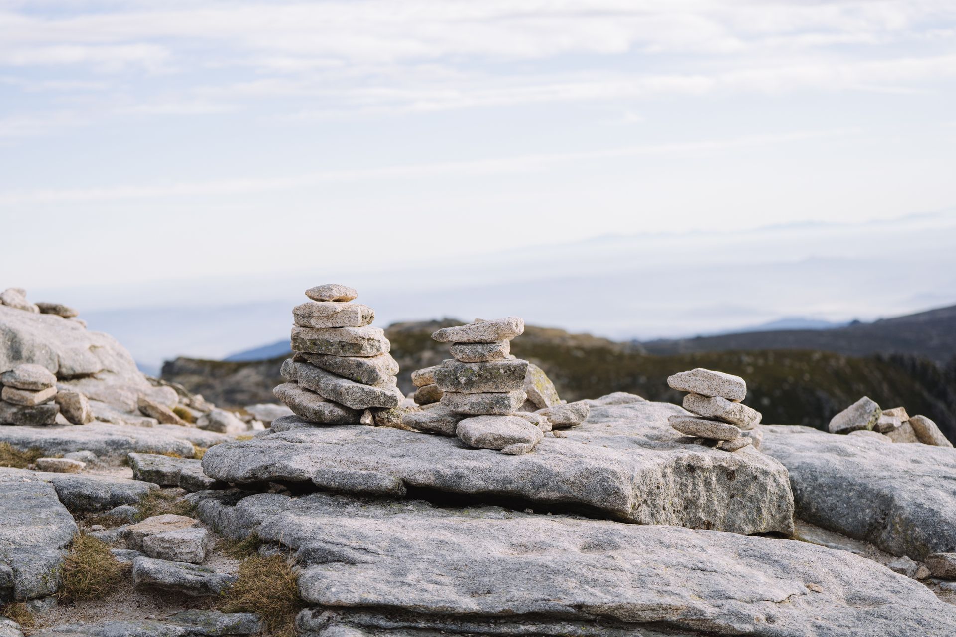Rock cairns atop a serene mountain plateau with a distant horizon view, conveying balance and tranquility.