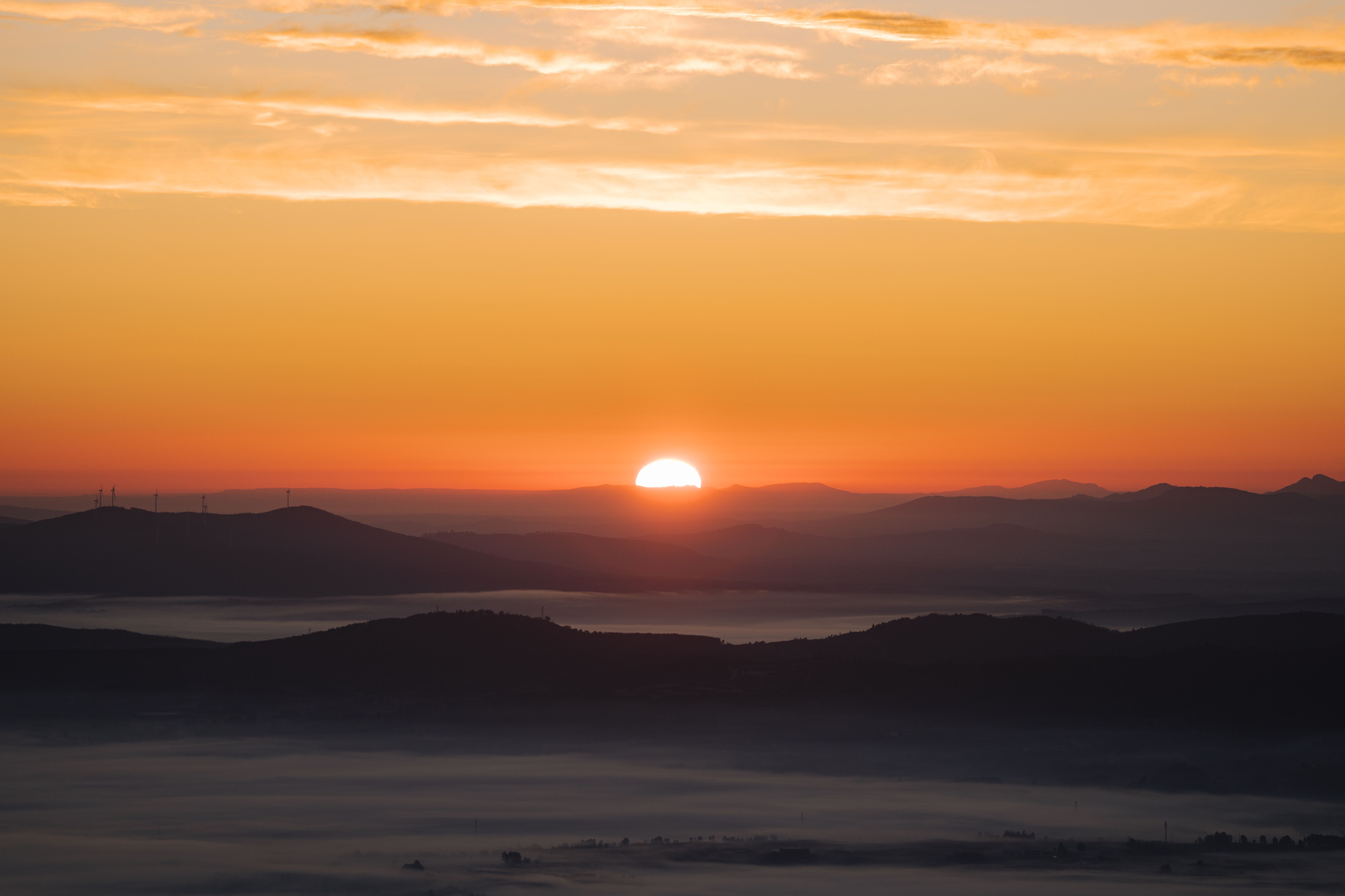 Tranquil sunrise over misty mountain valleys with vibrant sky hues.