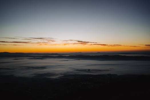 Stunning sunrise casting warm hues over a serene mist-covered landscape.