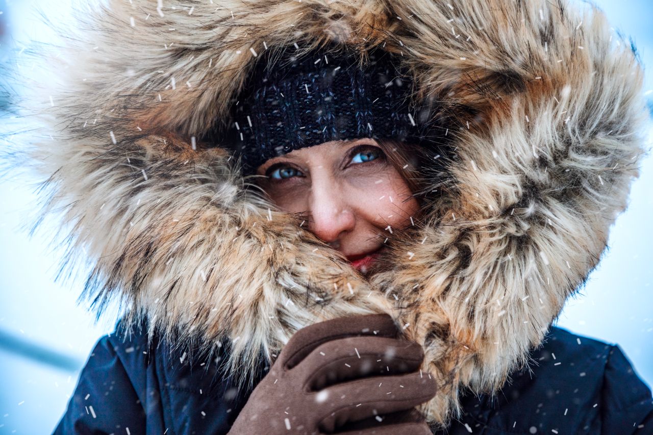 Close-up of a woman in a fur-trimmed hood in falling snow